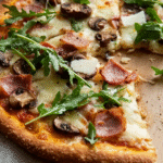 Blu­men­kohl-Piz­za mit Schin­ken, Cham­pi­gnons und Ru­co­la