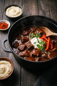Keto Gulasch im gusseisernen Topf mit Schmand, Paprikastreifen und Selleriepüree als Beilage