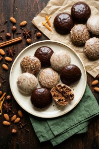 Keto Lebkuchen mit Schokoglasur und Zuckerglasur auf einem cremefarbenen Teller, daneben Mandeln, Haselnüsse und Zimtstangen